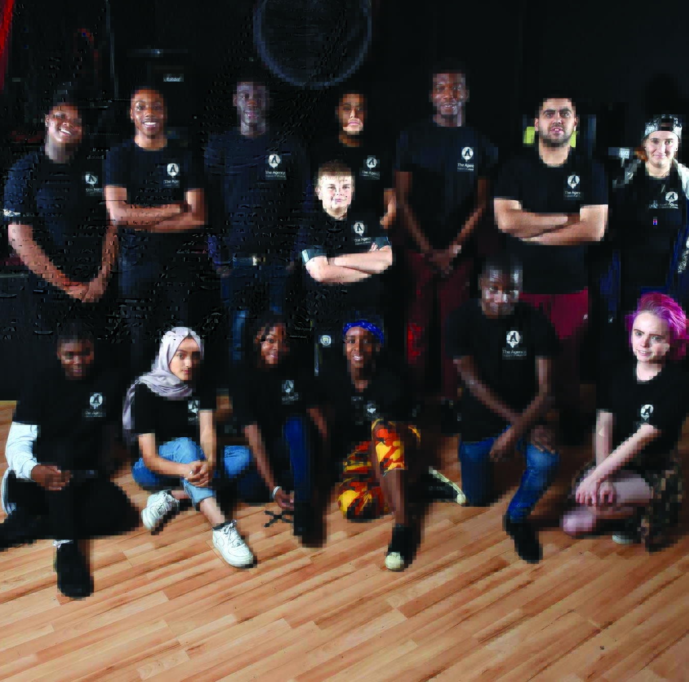 A group of young people, pictured indoors in a posed group wearing black Contact Theatre t-shirts